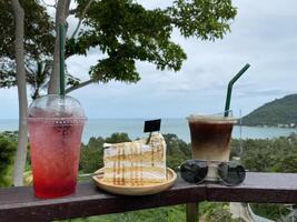 Savor vibrant drinks and delicious cake at ocean view point scenic nature setting for relaxing moments photo