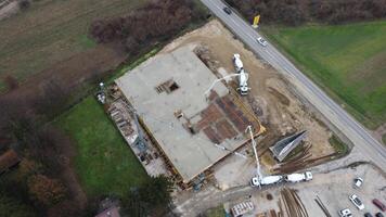 un aéreo ver capturado por un zumbido exhibiendo el en marcha construcción de un moderno edificio, destacando el trabajo en el estructura, andamio, y maquinaria en sitio foto