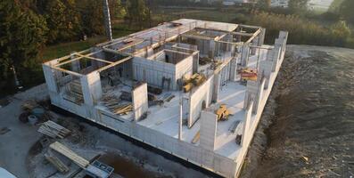 An aerial view captured by a drone showcasing the ongoing construction of a modern building, highlighting the work on the structure, scaffolding, and machinery on site photo