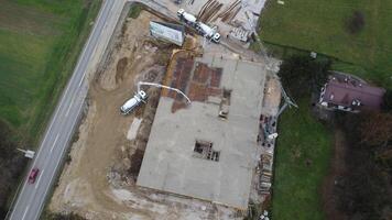 un aéreo ver capturado por un zumbido exhibiendo el en marcha construcción de un moderno edificio, destacando el trabajo en el estructura, andamio, y maquinaria en sitio foto