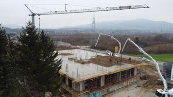 un aéreo ver capturado por un zumbido exhibiendo el en marcha construcción de un moderno edificio, destacando el trabajo en el estructura, andamio, y maquinaria en sitio foto