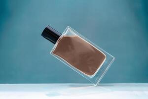 Suspended glass perfume bottle on blue background brown mocha color of 2025 year photo