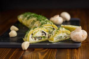 baked potato roll with cottage cheese filling with garlic and mushrooms, on a dark wooden table photo
