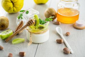Homemade yogurt in a glass jar with honey, kiwi, nuts. photo