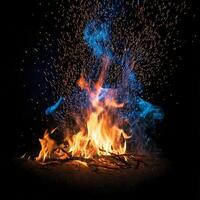 Fire burning in a black background with smoke and blue sparks photo