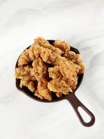 Heap of crispy fried chicken in a brown plate, isolated on white background with copy space. Close-up view photo