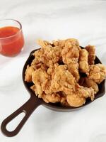 Heap of crispy fried chicken in a brown plate, isolated on white background with copy space. Close-up view photo