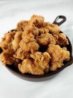 Heap of crispy fried chicken in a brown plate, isolated on white background with copy space. Close-up view photo