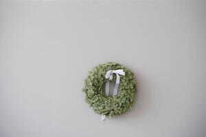 Christmas decorative wreath with a gray bow on the background of a gray concrete wall with a copy space photo