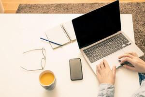 Person using a laptop computer on the modern white office desk table top view. photo