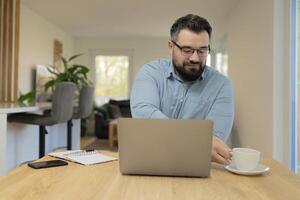 A happy man using a laptop while working at the home office. photo
