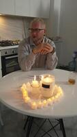 Man Candles Table - Man sitting at a table with candles lit in a kitchen setting. video