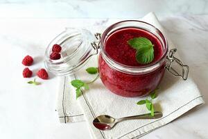 raspberry jam in a glass jar on a white background, tea with raspberries, vitamins for the body photo