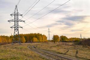 High-voltage power lines passing through a plowed field, on the background of a beautiful cloudy sky. photo