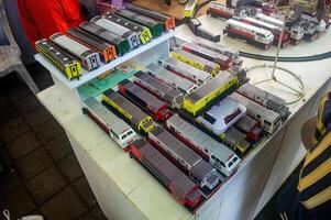 A vendor selling detailed miniature models of Indonesian trains displayed on a table at a market, showcasing various colorful train designs, Indonesia, 17 November 2024 photo