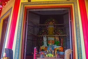 A vibrant temple entrance adorned with intricate patterns and a large statue under renovation, featuring offerings and decorations for Lunar New Year celebrations, Indonesia, 17 November 2024 photo