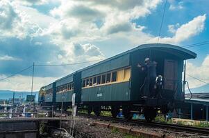 A historic tourist train in Ambarawa, showcasing vintage charm against a scenic backdrop of trees and traditional buildings. Indonesia, 17 November 2024 photo