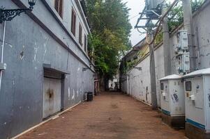 A narrow alleyway in Kota Tua Semarang, featuring weathered buildings and electrical infrastructure, Indonesia, 16 November 2024 photo