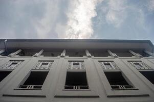 A low angle view of a historic building facade with intricate window designs and a cloudy sky background photo