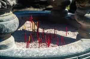 A close up of a stone incense burner filled with red and yellow incense sticks, commonly used in religious or spiritual rituals photo
