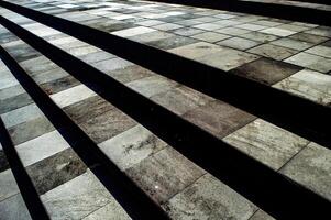 Modern stone steps with a checkered pattern of light and dark tiles, creating a striking visual effect with shadows photo