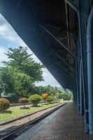 Scenic railway station platform with lush greenery and vibrant trees under a clear blue sky, perfect for travel and nature themes photo