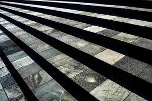 Modern stone steps with a checkered pattern of light and dark tiles, creating a striking visual effect with shadows photo