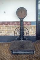 An antique weighing scale with a circular dial and a metal platform, set against a brick wall, Indonesia, 17 November 2024 photo