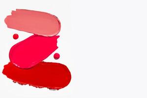 Cosmetic texture of lipstick smears in a variety of red shades with empty space on a light white background. Beauty product stroke swatch. photo
