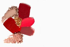 Bright and colorful cosmetics composition with lipstick, eyeshadow, bronzer, and powder textures with empty space on a light white background. photo