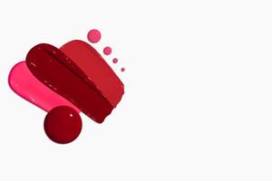 Composition of red lipstick smears and drops in various shades, including dark red, light red, burgundy, and pink, isolated on a light background. photo