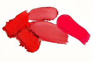 Matte lipstick smears and strokes in red tones on a light white background. Cosmetic product composition. photo