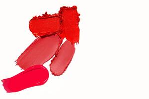 Red lipstick smudges and swatches in a textured composition with empty space on a light white background. Matte lipstick stroke design. photo
