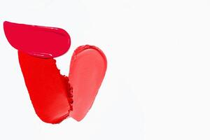 Textured strokes of lipstick in various red shades with empty space on a light white background. Cosmetic product smear sample. photo