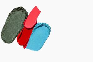 Bright and colorful composition of lipstick, eyeshadow, bronzer, glitter, and powder textures with empty space on a light white background. photo