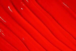Texture of red lipstick with lines covering the entire image. Bold cosmetic background, vibrant color. photo
