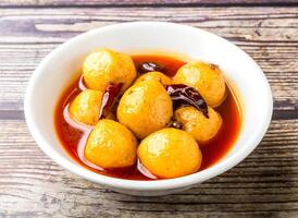 Spicy fish balls with red chilli and sauce served in bowl isolated on wooden table side view of hong kong food photo