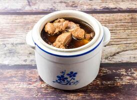 Maca snail head stewed in chicken soup served in clay pot broth isolated on wooden table side view of hong kong food photo