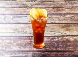 Frozen Lemon Tea topped with lime slice and ice cube served in glass isolated on wooden table side view of hong kong iced tea drink photo