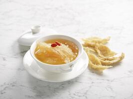Double boiled Supreme Birds Nest with Superior Broth served in a bowl side view on grey marble background photo