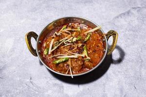 Mutton Karahi topped with ginger and green chilli served in karahi isolated on grey background side view of indian, bangladeshi and pakistani food photo