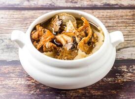 Gastrodia fish head soup topped with fragrant truffles served in broth isolated on wooden table side view of hong kong food photo
