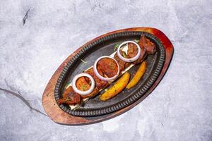 Beef Tikka Boti Kabab or Fish Tikka Kebab with naan bread, onion and fries served on a sizzling plate isolated on grey background side view of indian, bangladeshi and pakistani bbq food photo