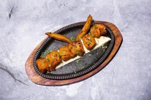 Achari Fish Tikka kabab with nan, breab and fries served on a sizzling plate isolated on grey background side view of indian, bangladeshi and pakistani bbq food photo