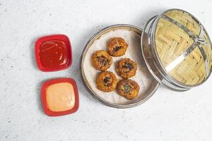 Fried Chicken with Lemon Grass Shumai with mayo dip and tomato sauce served in bamboo steamer isolated on white background top view of bangladeshi, indian and chinese dim sum food photo
