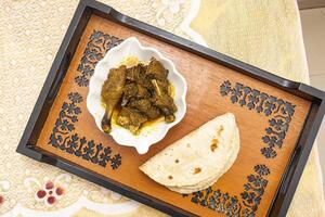 Duck Curry with Roti served on tray dish isolated on dinning table top view of bangladeshi food photo