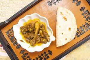 Spicy Desi Chicken Curry with Roti served on tray dish isolated on dinning table top view of bangladeshi food photo