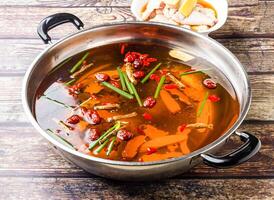 Huadiao Drunken Chicken Hotpot topping with scallions and red date or jujube served in steel pot isolated on wooden table side view of hong kong food photo