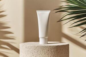 Mockup of cosmetic tube cream 50ml on stone stand on beige background minimalist with green leaves palm. Natural hard lighting and shadows photo