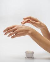 Female hands apply cream white jar with cream stands on background photo